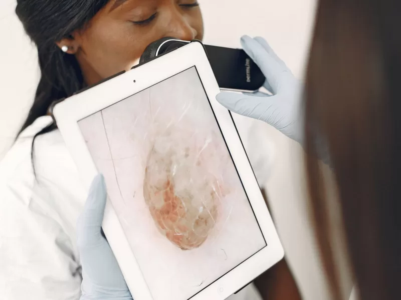 Profissional de saúde realizando exame de pele com tecnologia avançada