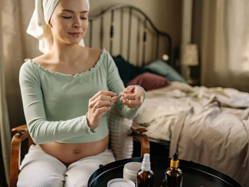 Gestante aplicando produto de skincare durante rotina matinal